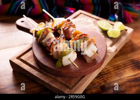 Hausgemachte Spieße mit Fleisch und gegrilltem Gemüse, serviert auf einem rustikalen Holzbrett, auch bekannt als Brochetten, Chuzo oder Pincho. Stockfoto