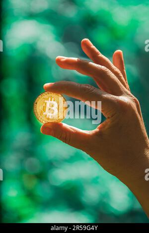 Eine Goldmünze in der Hand zu halten. Handel an der Kryptowährungsbörse. Elektronisches dezentralisiertes Geldkonzept. Bitcoin ist eine bequeme Bezahlung Stockfoto