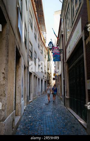 Zwei jüngere Touristen, die durch eine der engen Gassen im Alfama-Viertel von Lissabon spazieren Stockfoto