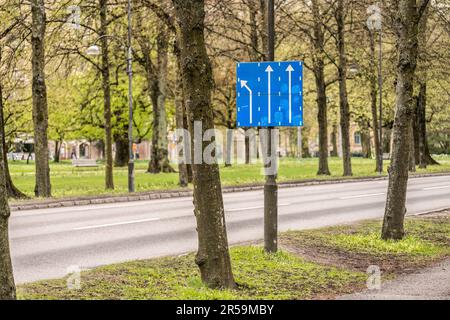 Das Blye-Schild zeigt zwei Fahrspuren, die weiter fahren, und eine links abbiegen Stockfoto