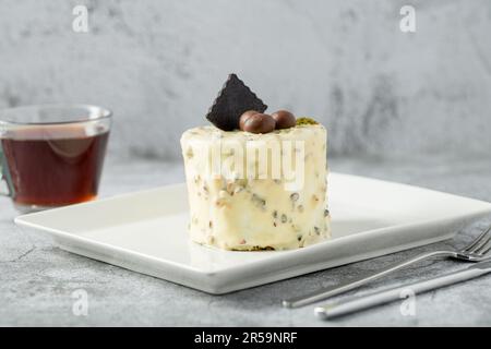 Ein-Personen-Minikuchen mit Pistazien und weißer Schokolade auf einem weißen Porzellanteller Stockfoto