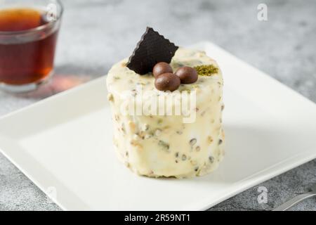 Ein-Personen-Minikuchen mit Pistazien und weißer Schokolade auf einem weißen Porzellanteller Stockfoto