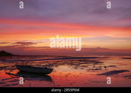 Farbenfroher Sonnenuntergang mit dem Fischerboot am Walakiri Beach in der Nähe von Waingapu auf Sumba Island, East Nusa Tenggara, Indonesien Stockfoto