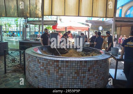 Taschkent, Usbekistan - 5. Mai 2023: Bwsh kazan. Koch rührt Reis in einem Kessel. Traditioneller Kochpilaf. Stockfoto