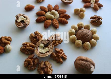 Blumenverzierung auf einer weißen Oberfläche von geschälten Nüssen verschiedener Sorten Stockfoto