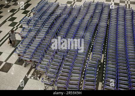 Ein Reisender, der einen Flughafen-Trolley am Flughafen Changi, Singapur, bekommt. Stockfoto