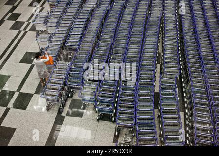 Ein Reisender, der einen Flughafen-Trolley am Flughafen Changi, Singapur, bekommt. Stockfoto