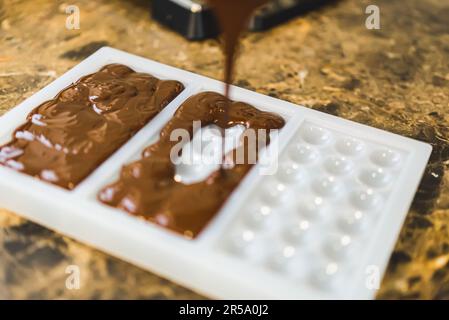 Der Küchenchef bereitet temperierte Schokolade in Barform zu - Schokoladenstücke auf der Theke. Hochwertiges Foto Stockfoto