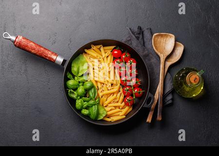 Eine lebendige Darstellung der italienischen Flagge mit Pasta, Basilikum und Tomaten, wunderschön präsentiert in einer Pfanne. Flach verlegt Stockfoto