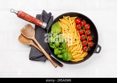 Eine lebendige Darstellung der italienischen Flagge mit Pasta, Basilikum und Tomaten, wunderschön präsentiert in einer Pfanne. Flach verlegt Stockfoto