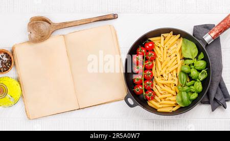 Eine lebendige Darstellung der italienischen Flagge mit Pasta, Basilikum und Tomaten, wunderschön präsentiert in einer Bratpfanne, und Kochbuchseite für Ihr Stockfoto