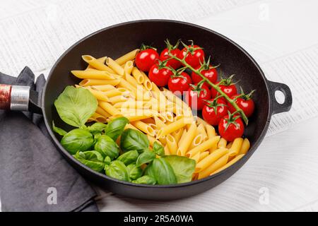 Eine lebendige Darstellung der italienischen Flagge mit Pasta, Basilikum und Tomaten, wunderschön präsentiert in einer Pfanne Stockfoto