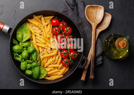 Eine lebendige Darstellung der italienischen Flagge mit Pasta, Basilikum und Tomaten, wunderschön präsentiert in einer Pfanne. Flach verlegt Stockfoto