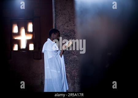 Ein äthiopisch-orthodoxer Christenmann liest aus der Schrift in Bet Medhane Alem, Lalibela, Nordäthiopien. Stockfoto