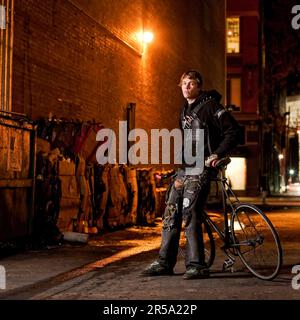 Fixed Gear Rider poses in a dark ally with his bike. Stockfoto