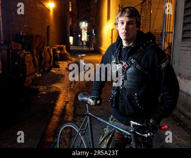 Fixed Gear Rider poses in a dark ally with his bike. Stockfoto