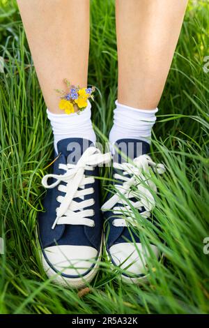 Wunderschöne Freizeitschuhe mit zarten, leuchtenden Farben in Socken. Modische, stylische sportliche Freizeitschuhe. Blumen in blauen Turnschuhen, ein Klassiker Stockfoto