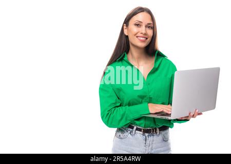 Gut gepflegte braune, langhaarige junge Geschäftsfrau in einem grünen Hemd arbeitet in DER IT-Abteilung auf weißem Hintergrund mit Kopierbereich Stockfoto