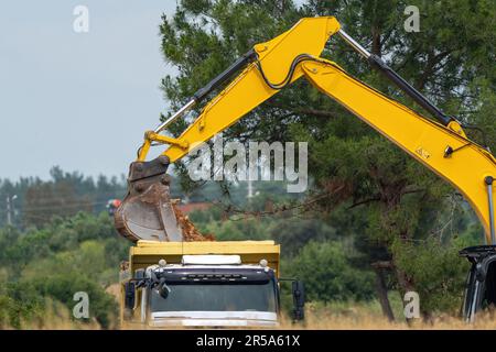 Bagger, der Erde auf einen Lkw lädt, Schaufel zum Laden von Erde Stockfoto