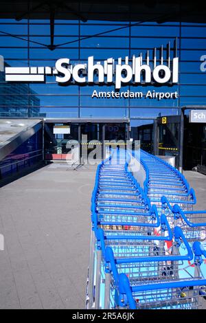 Amsterdam, Niederlande - August 10 2022: Gepäckwagen vor der Ankunftshalle Flughafen Amsterdam Schiphol an sonnigen Tagen. Stockfoto