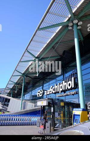 Amsterdam, Niederlande - August 10 2022: Gepäckwagen vor der Ankunftshalle Flughafen Amsterdam Schiphol an sonnigen Tagen. Stockfoto