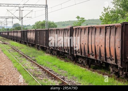 Foto mehrerer Wagen, die im halb verlassenen Güterbahnhof Serbiens stehen, mit offener Hauptbahn oder Gondel. Offene Wagen (Lkw in Großbritannien) bilden ein l Stockfoto
