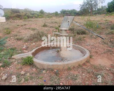 Wasser tritt aus der Bohrung der Deepwell-Handpumpe aus Stockfoto