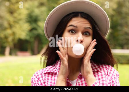 Schöne junge Frau, die draußen Kaugummi bläst Stockfoto