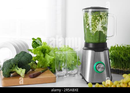 Mixer mit köstlichem Smoothie und Zutaten in der Küche Stockfoto