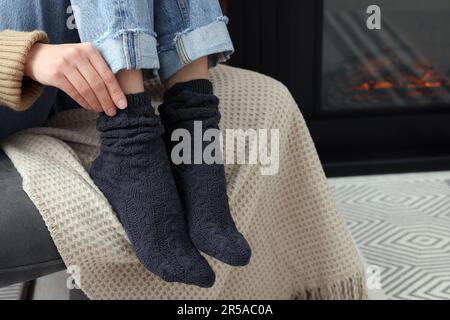 Eine Frau in warmen Socken, die sich zu Hause am Kamin entspannt Stockfoto