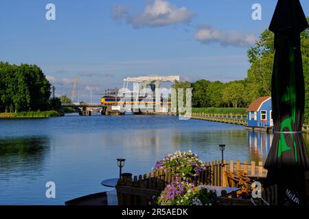 Weesp, Niederlande - Juli 05. 2022: Holländischer Personenzug, der eine Brücke in Weesp über den Fluss Vecht passiert. Stockfoto