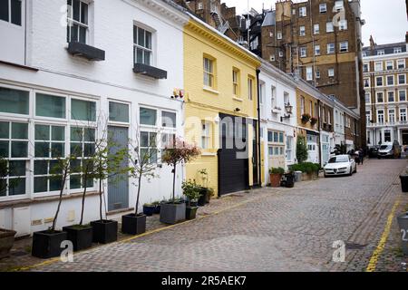 London, Großbritannien - 27. April 2022: Terrassenhäuser in einer Kopfsteinpflasterstraße in den Altherstone Mews in Kensington. Stockfoto