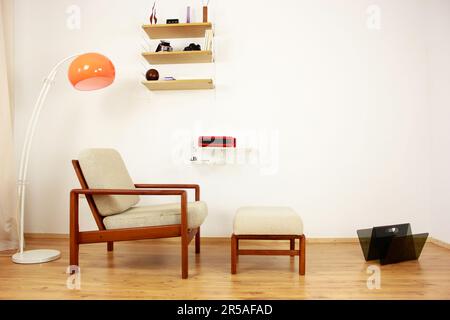 Sessel mit osmanischem dänischem Design in einem gemütlichen, modern eingerichteten Wohnzimmer im Stil 60s mit Wandablage und Schreibmaschine im Hintergrund-Ora Stockfoto