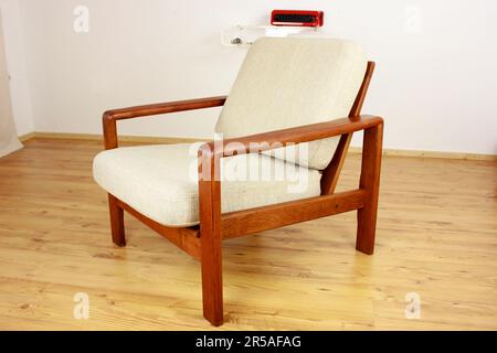 Sessel mit osmanischem dänischem Design in einem gemütlichen, modern eingerichteten Wohnzimmer im Stil 60s mit Wandablage und Schreibmaschine im Hintergrund-Ora Stockfoto