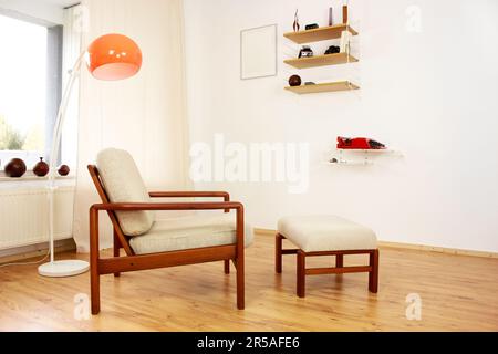 Sessel mit osmanischem dänischem Design in einem gemütlichen, modern eingerichteten Wohnzimmer im Stil 60s mit Wandablage und Schreibmaschine im Hintergrund-Ora Stockfoto