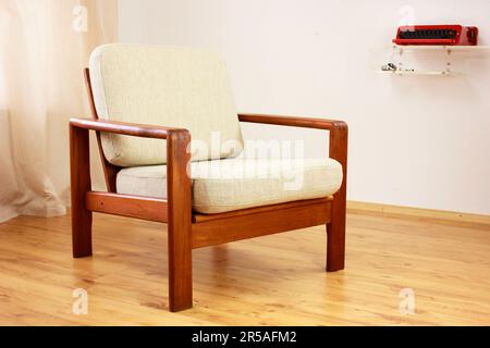 Sessel mit osmanischem dänischem Design in einem gemütlichen, modern eingerichteten Wohnzimmer im Stil 60s mit Wandablage und Schreibmaschine im Hintergrund-Ora Stockfoto