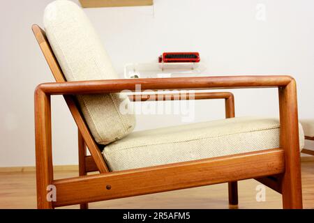 Sessel mit osmanischem dänischem Design in einem gemütlichen, modern eingerichteten Wohnzimmer im Stil 60s mit Wandablage und Schreibmaschine im Hintergrund-Ora Stockfoto