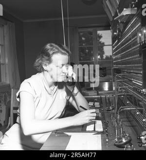 Telefonie in den 1950er. Eine Frau, die an einer Telefonzentrale arbeitet, als Vermittlung. Ein manuell betriebenes Telefonkommunikationssystem, bei dem die eingehenden Anrufe vom Betreiber weitergeleitet und an eine andere Telefonnummer umgeleitet wurden, in diesem Fall lokal innerhalb des Gebäudes, das ein Unternehmen oder eine Organisation mit vielen internen Telefonleitungen bedient. Die Telefonzentrale konnte Nachrichten entgegennehmen und Sie in die Warteschleife setzen, wenn die Leitung besetzt war. Schweden 1953. Conard Ref. 2489 Stockfoto