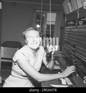 Telefonie in den 1950er. Eine Frau, die an einer Telefonzentrale arbeitet, als Vermittlung. Ein manuell betriebenes Telefonkommunikationssystem, bei dem die eingehenden Anrufe vom Betreiber weitergeleitet und an eine andere Telefonnummer umgeleitet wurden, in diesem Fall lokal innerhalb des Gebäudes, das ein Unternehmen oder eine Organisation mit vielen internen Telefonleitungen bedient. Die Telefonzentrale konnte Nachrichten entgegennehmen und Sie in die Warteschleife setzen, wenn die Leitung besetzt war. Schweden 1953. Conard Ref. 2489 Stockfoto