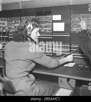 Telefonie in den 1950er. Frauen, die in einer Telefonzentrale arbeiten, als Telefonisten. Ein manuell betriebenes Telefonkommunikationssystem, bei dem die eingehenden Anrufe vom Betreiber weitergeleitet und an eine andere Telefonnummer umgeleitet wurden, in diesem Fall lokal innerhalb des Gebäudes, das ein Unternehmen oder eine Organisation mit vielen internen Telefonleitungen bedient. Die Telefonzentrale konnte Nachrichten entgegennehmen und Sie in die Warteschleife setzen, wenn die Leitung besetzt war. Schweden 1953. Kristoffersson Ref. BM99-8 Stockfoto