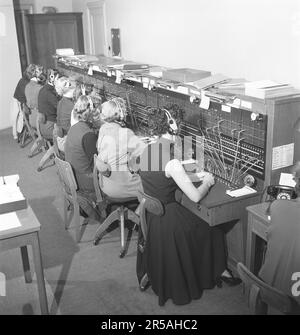 Telefonie in den 1950er. Frauen, die in einer Telefonzentrale arbeiten, als Telefonisten. Ein manuell betriebenes Telefonkommunikationssystem, bei dem die eingehenden Anrufe vom Betreiber weitergeleitet und an eine andere Telefonnummer umgeleitet wurden, in diesem Fall lokal innerhalb des Gebäudes, das ein Unternehmen oder eine Organisation mit vielen internen Telefonleitungen bedient. Die Telefonzentrale konnte Nachrichten entgegennehmen und Sie in die Warteschleife setzen, wenn die Leitung besetzt war. Schweden 1953. Kristoffersson Ref. BM71-1 Stockfoto