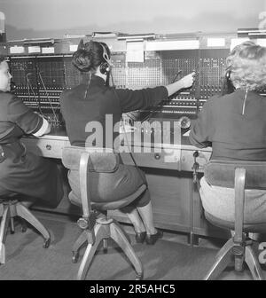 Telefonie in den 1950er. Frauen, die in einer Telefonzentrale arbeiten, als Telefonisten. Ein manuell betriebenes Telefonkommunikationssystem, bei dem die eingehenden Anrufe vom Betreiber weitergeleitet und an eine andere Telefonnummer umgeleitet wurden, in diesem Fall lokal innerhalb des Gebäudes, das ein Unternehmen oder eine Organisation mit vielen internen Telefonleitungen bedient. Die Telefonzentrale konnte Nachrichten entgegennehmen und Sie in die Warteschleife setzen, wenn die Leitung besetzt war. Schweden 1953. Kristoffersson Ref. BM70-11 Stockfoto