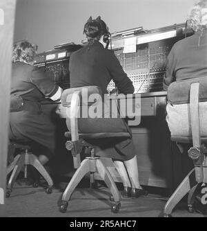 Telefonie in den 1950er. Frauen, die in einer Telefonzentrale arbeiten, als Telefonisten. Ein manuell betriebenes Telefonkommunikationssystem, bei dem die eingehenden Anrufe vom Betreiber weitergeleitet und an eine andere Telefonnummer umgeleitet wurden, in diesem Fall lokal innerhalb des Gebäudes, das ein Unternehmen oder eine Organisation mit vielen internen Telefonleitungen bedient. Die Telefonzentrale konnte Nachrichten entgegennehmen und Sie in die Warteschleife setzen, wenn die Leitung besetzt war. Schweden 1953. Kristoffersson Ref. BM70-12 Stockfoto