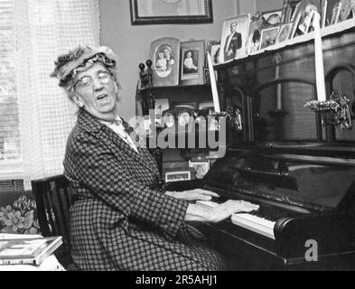 Klavier spielen. Eine ältere Dame am Klavier, die das Lied singt, um die Musik zu begleiten. Sie ist die Schauspielerin Julia Caesar 1885-1971 zu Hause. Schweden 1965 Stockfoto