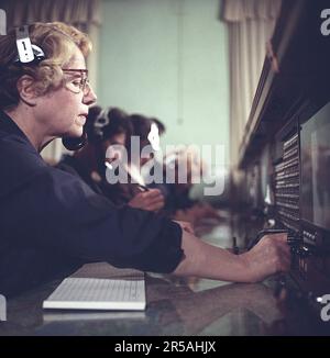 Telefonie in den 1950er. Eine Frau, die an einer Telefonzentrale arbeitet, als Vermittlung. Ein manuell betriebenes Telefonkommunikationssystem, bei dem die eingehenden Anrufe vom Betreiber weitergeleitet und an eine andere Telefonnummer umgeleitet wurden, in diesem Fall lokal innerhalb des Gebäudes, das ein Unternehmen oder eine Organisation mit vielen internen Telefonleitungen bedient. Die Telefonzentrale konnte Nachrichten entgegennehmen und Sie in die Warteschleife setzen, wenn die Leitung besetzt war. Schweden 1953. Dieses Bild wird an einer Telefonzentrale eines Taxiunternehmens in Stockholm aufgenommen, wo Anrufe von Kunden und Fahrern entgegengenommen und weitergeleitet werden. S Stockfoto