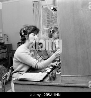 Telefonie in den 1960er. Frau, die in einer Telefonzentrale arbeitet, als Vermittlung. Ein manuell betriebenes Telefonkommunikationssystem, bei dem die eingehenden Anrufe vom Betreiber weitergeleitet und an eine andere Telefonnummer umgeleitet wurden, in diesem Fall lokal innerhalb des Gebäudes, das ein Unternehmen oder eine Organisation mit vielen internen Telefonleitungen bedient. Die Telefonzentrale konnte Nachrichten entgegennehmen und Sie in die Warteschleife setzen, wenn die Leitung besetzt war. Schweden 1963 Stockfoto