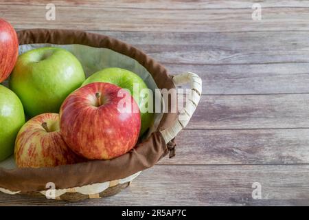 Ein Holzkorb mit frisch gepflückten roten und grünen Äpfeln Stockfoto