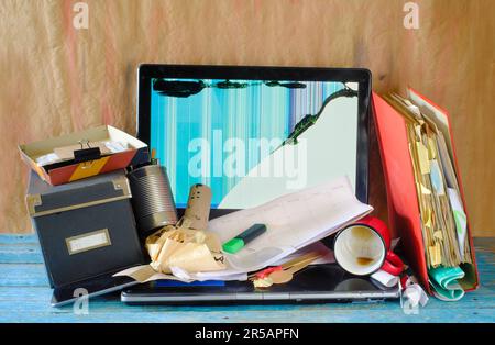 Unordentlicher Arbeitsplatz, chaotisches Büro, überarbeitet, Bürokratie, Bürokratie-Konzept mit schäbigem Schreibtisch, defekter Laptop und verschiedene Büromaterialien, kostenlose Kopie sp Stockfoto