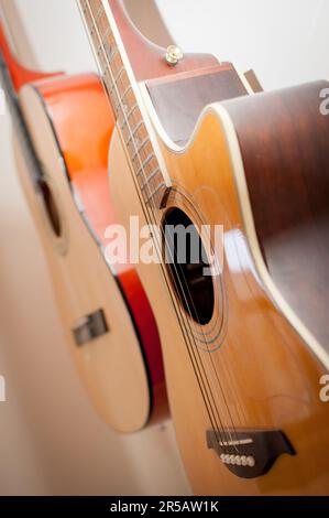 Zwei klassische Akustikgitarren, die an der Wand hängen. Klassische Akustikgitarren im Vintage-Stil. Instrumente aus Holz. Stockfoto