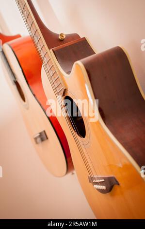 Zwei klassische Akustikgitarren, die an der Wand hängen. Klassische Akustikgitarren im Vintage-Stil. Instrumente aus Holz. Stockfoto